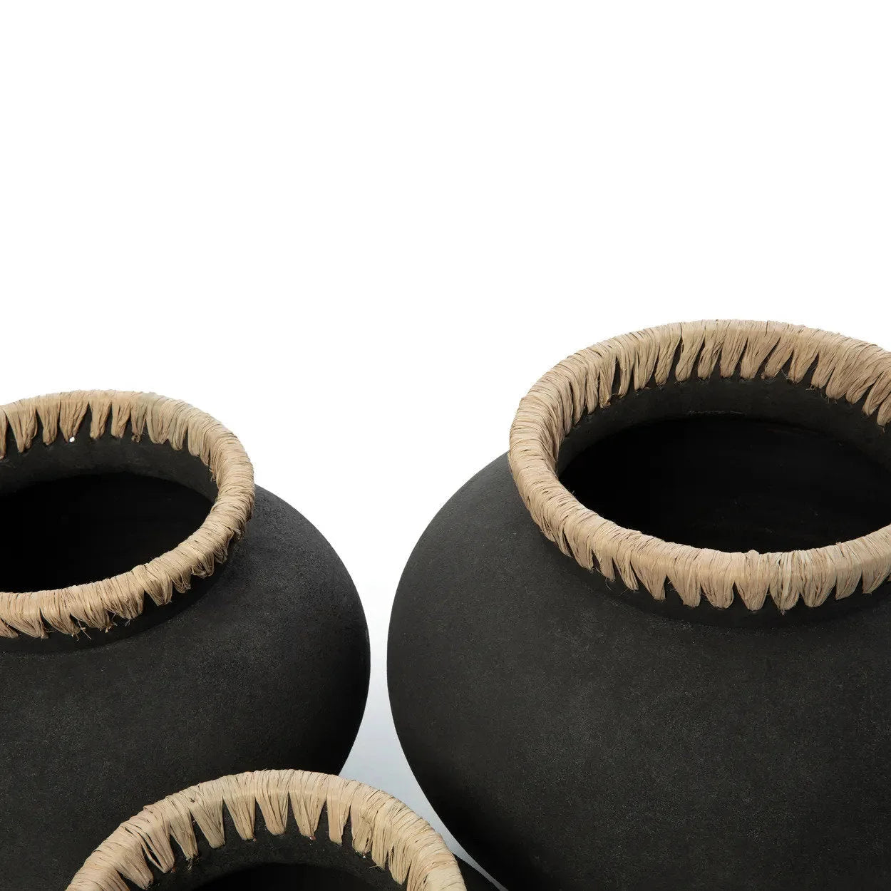 Trois pots en céramique noire avec rives texturées légères, vase rond en terre cuite et raphia