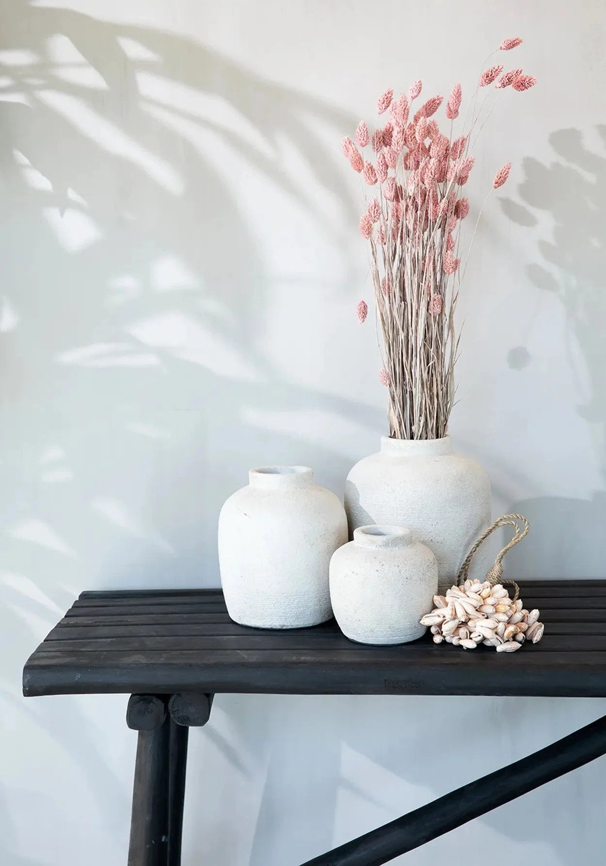 Vase rond en terre cuite beige avec texture, contenant des tiges florales séchées roses